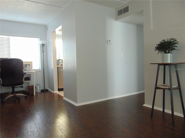 office with a textured ceiling, wood finished floors, visible vents, and baseboards