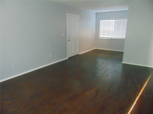 empty room with dark wood finished floors and baseboards