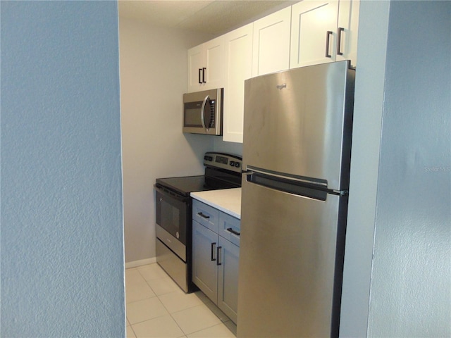 kitchen with light tile patterned floors, stainless steel appliances, baseboards, white cabinets, and light countertops