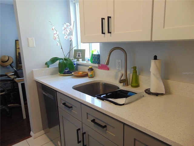 kitchen with a sink, light stone countertops, white cabinetry, and stainless steel dishwasher