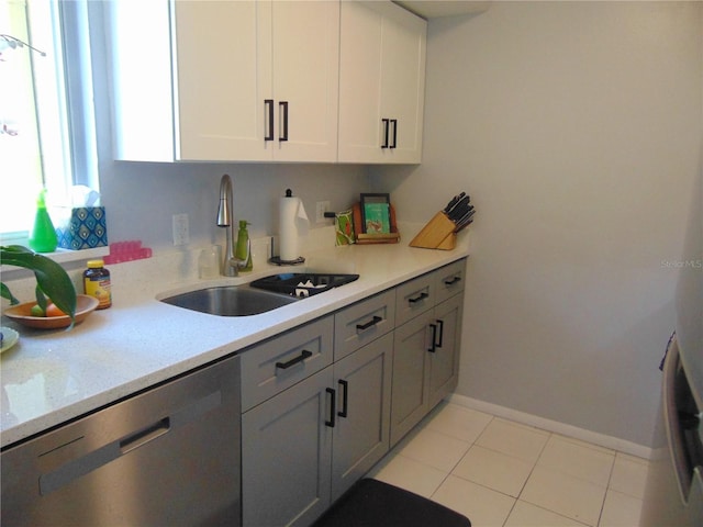 kitchen with a sink, baseboards, white cabinets, light countertops, and stainless steel dishwasher