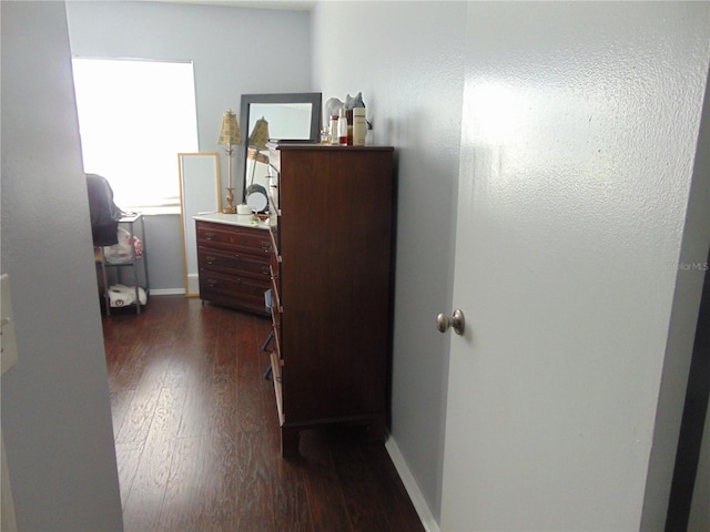 hallway featuring baseboards and dark wood-type flooring