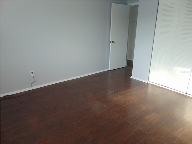 empty room featuring dark wood finished floors and baseboards