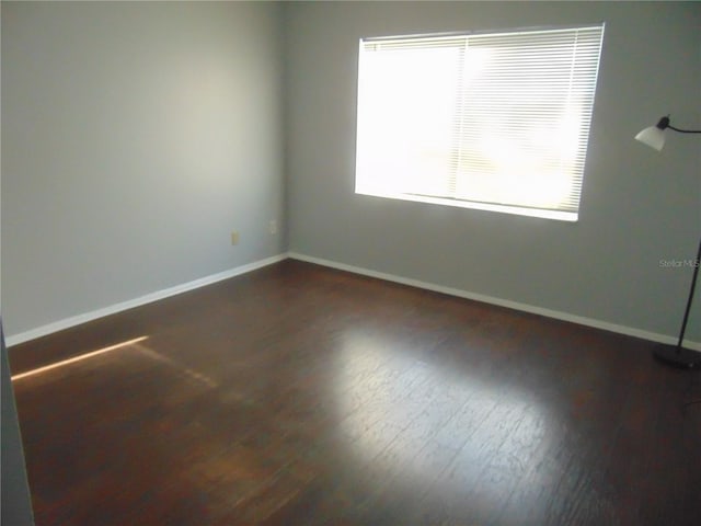 unfurnished room featuring dark wood-style flooring and baseboards