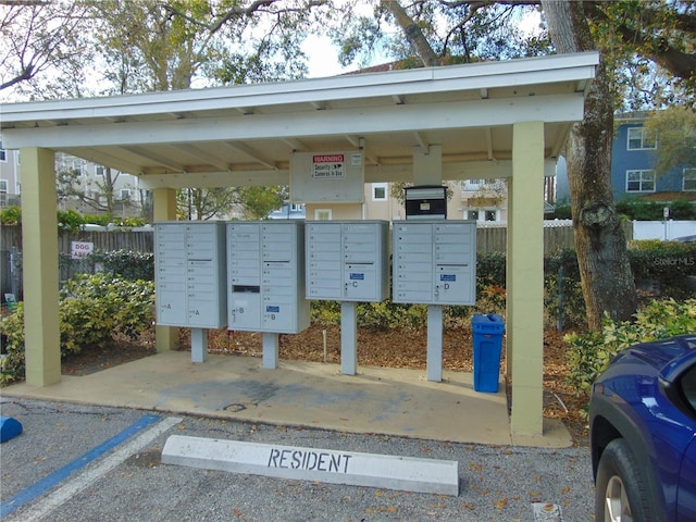 surrounding community with a parking lot, fence, and mail area