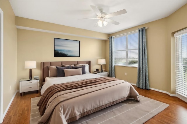 bedroom with multiple windows, ceiling fan, and hardwood / wood-style flooring