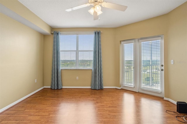 spare room with plenty of natural light, ceiling fan, and light wood-type flooring