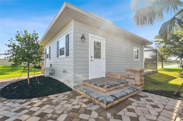 doorway to property featuring a lawn and a patio