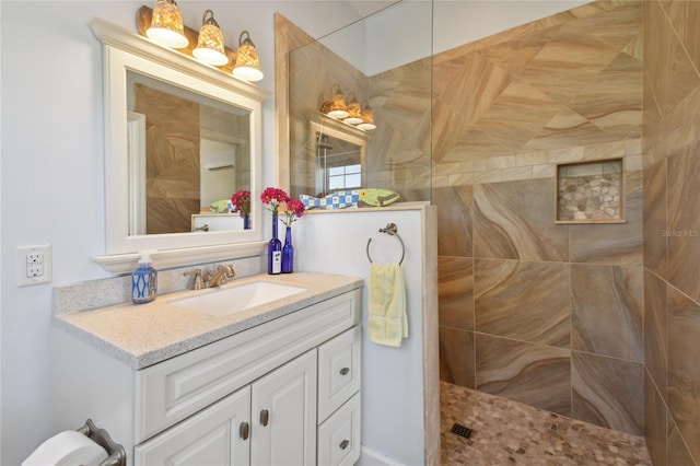 bathroom featuring tiled shower and vanity