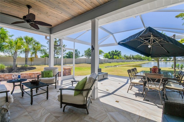 view of patio with a lanai, a water view, and ceiling fan