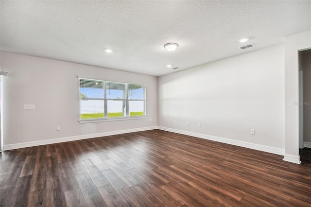 empty room featuring a textured ceiling and dark wood-type flooring