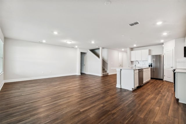 kitchen featuring dark hardwood / wood-style floors, sink, backsplash, a center island with sink, and appliances with stainless steel finishes