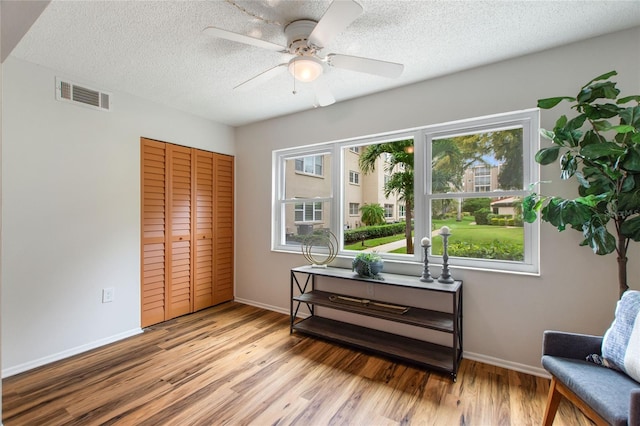 sitting room featuring a textured ceiling, ceiling fan, and light hardwood / wood-style floors