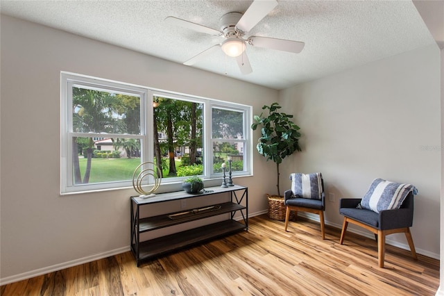 living area featuring ceiling fan, a textured ceiling, and light hardwood / wood-style flooring