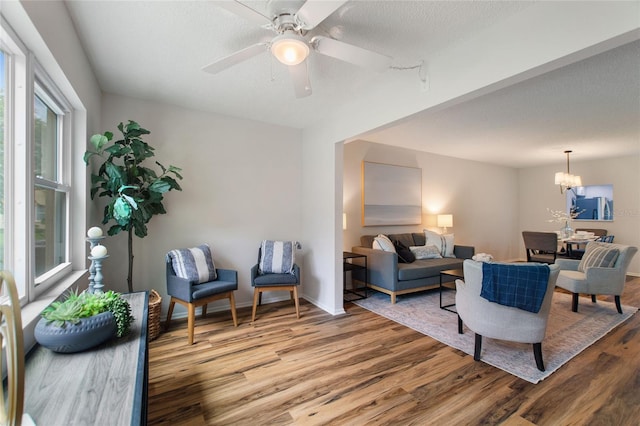 living room featuring a textured ceiling, ceiling fan with notable chandelier, and hardwood / wood-style flooring