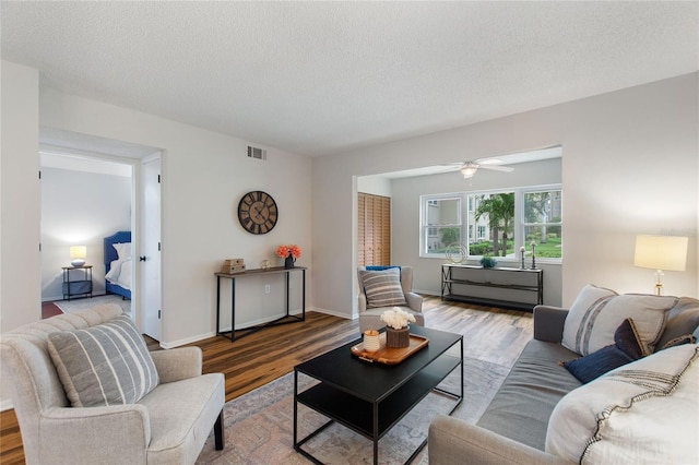 living room featuring ceiling fan, light hardwood / wood-style floors, and a textured ceiling