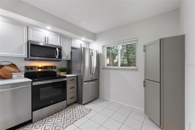 kitchen featuring a textured ceiling, stainless steel appliances, light tile patterned floors, and white cabinets