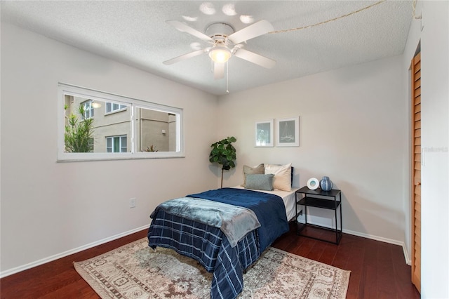 bedroom featuring dark wood-type flooring, ceiling fan, and a textured ceiling