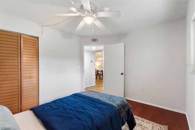 bedroom with a textured ceiling, ceiling fan, a closet, and hardwood / wood-style flooring