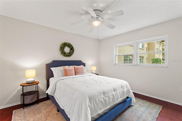 bedroom with dark wood-type flooring, ceiling fan, and a textured ceiling