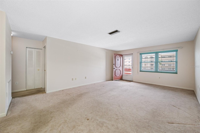 carpeted empty room featuring a textured ceiling