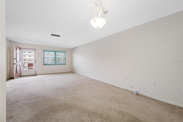 unfurnished room featuring light colored carpet and a textured ceiling