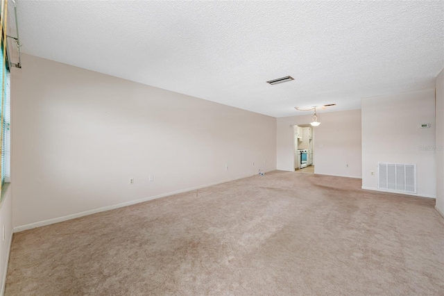 carpeted empty room featuring a textured ceiling