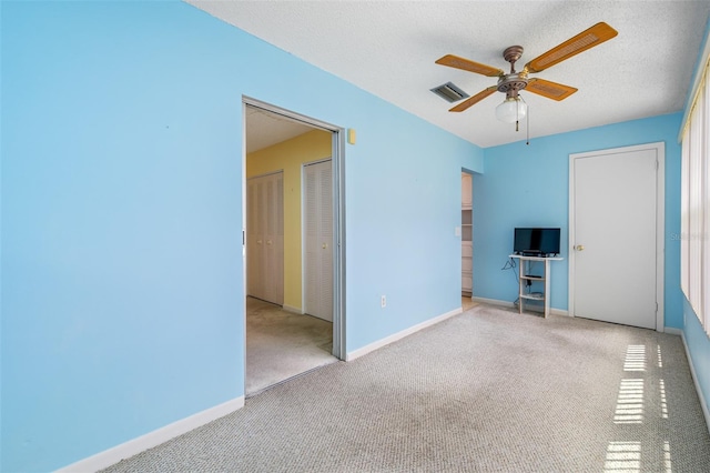 carpeted spare room with a textured ceiling and ceiling fan