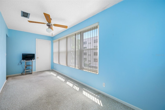 interior space with a textured ceiling, carpet, and ceiling fan