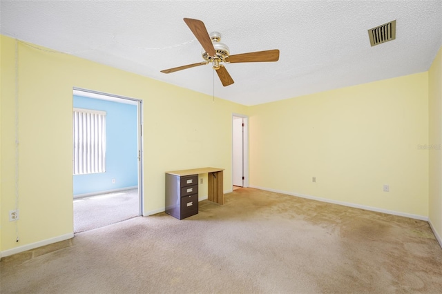 spare room featuring a textured ceiling, light colored carpet, and ceiling fan