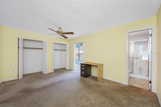 unfurnished bedroom featuring a textured ceiling, ceiling fan, carpet, two closets, and ensuite bathroom