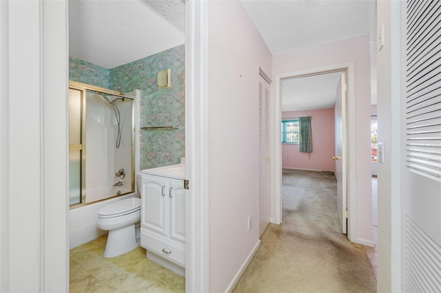 full bathroom featuring shower / bath combination with glass door, vanity, toilet, and a textured ceiling