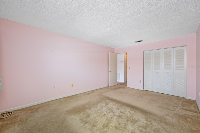 unfurnished bedroom with a textured ceiling, carpet flooring, and a closet