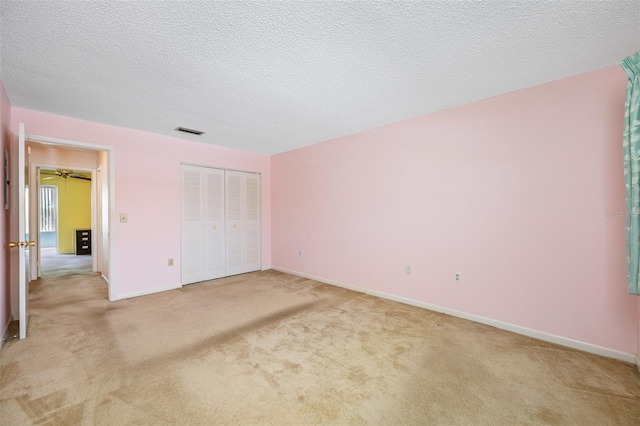 unfurnished bedroom with a textured ceiling, a closet, and light carpet