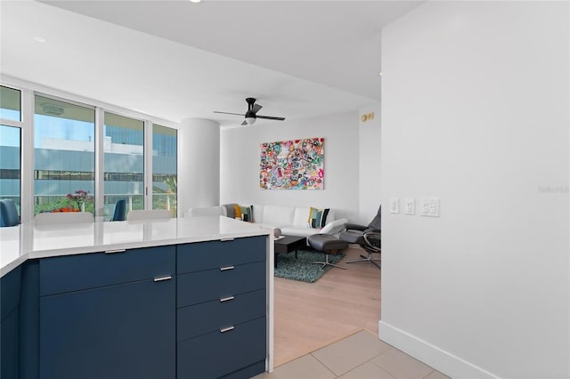 kitchen with blue cabinets, ceiling fan, and light hardwood / wood-style floors