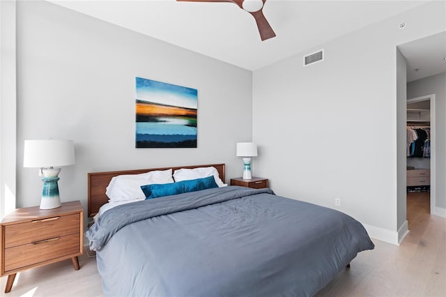 bedroom featuring light hardwood / wood-style flooring, a walk in closet, ceiling fan, and a closet