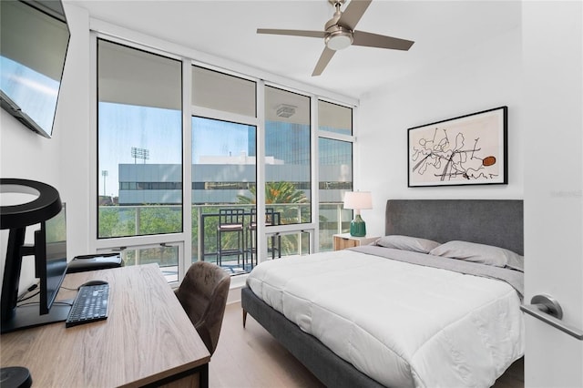 bedroom with hardwood / wood-style floors, floor to ceiling windows, access to exterior, and ceiling fan