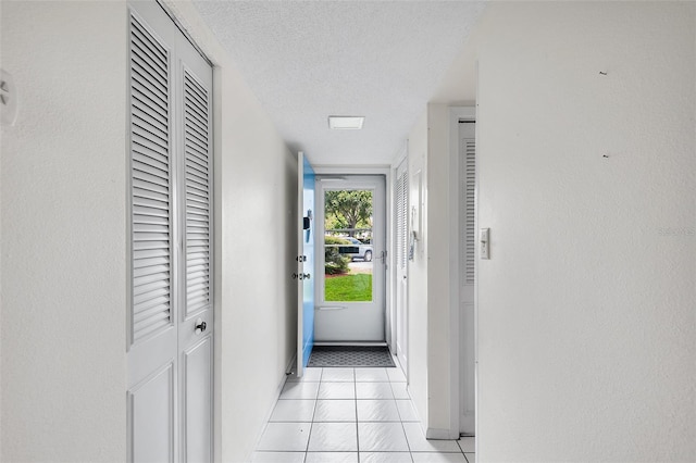 hallway featuring a textured ceiling and light tile patterned flooring