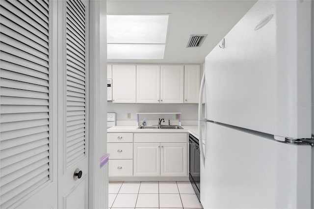 kitchen featuring white refrigerator, light tile patterned floors, white cabinets, and sink