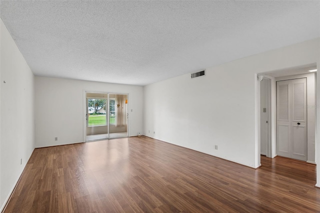 unfurnished room featuring a textured ceiling and dark hardwood / wood-style floors