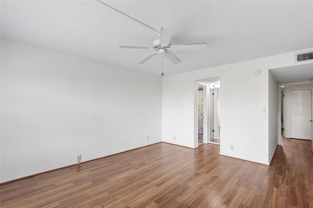 empty room featuring dark hardwood / wood-style flooring, ceiling fan, and a textured ceiling