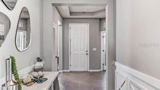 hallway featuring a raised ceiling and dark tile patterned floors