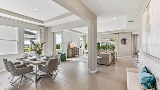 dining room with a healthy amount of sunlight, a raised ceiling, and light tile patterned floors