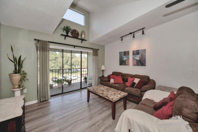 living room featuring vaulted ceiling, a textured ceiling, and light wood-type flooring