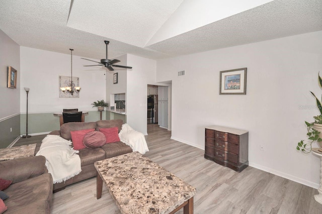 living room with high vaulted ceiling, a textured ceiling, light hardwood / wood-style flooring, and ceiling fan with notable chandelier