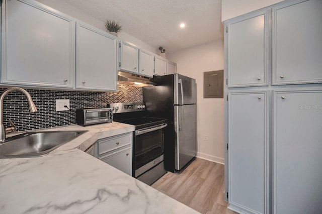 kitchen featuring decorative backsplash, light hardwood / wood-style flooring, stainless steel appliances, sink, and light stone counters