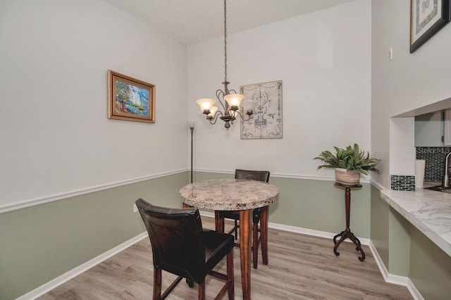 dining area featuring light hardwood / wood-style flooring, a textured ceiling, and a chandelier