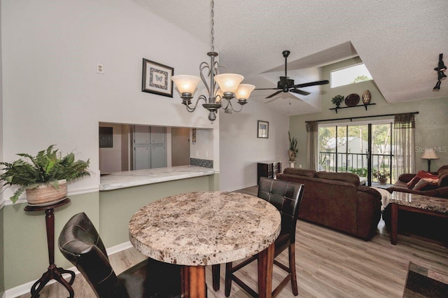 dining area featuring lofted ceiling, light hardwood / wood-style floors, a textured ceiling, and ceiling fan with notable chandelier