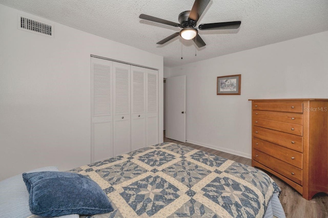 bedroom featuring a closet, ceiling fan, hardwood / wood-style flooring, and a textured ceiling