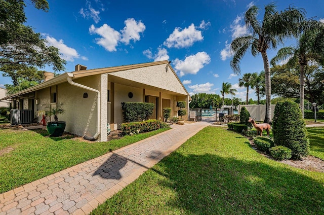 view of front of house with a front lawn and central AC